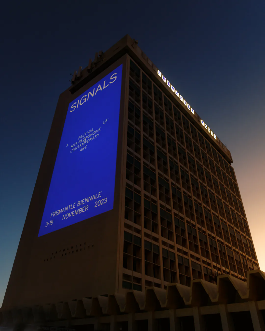 The Signals identity projected in blue onto the Fremantle Ports building at night