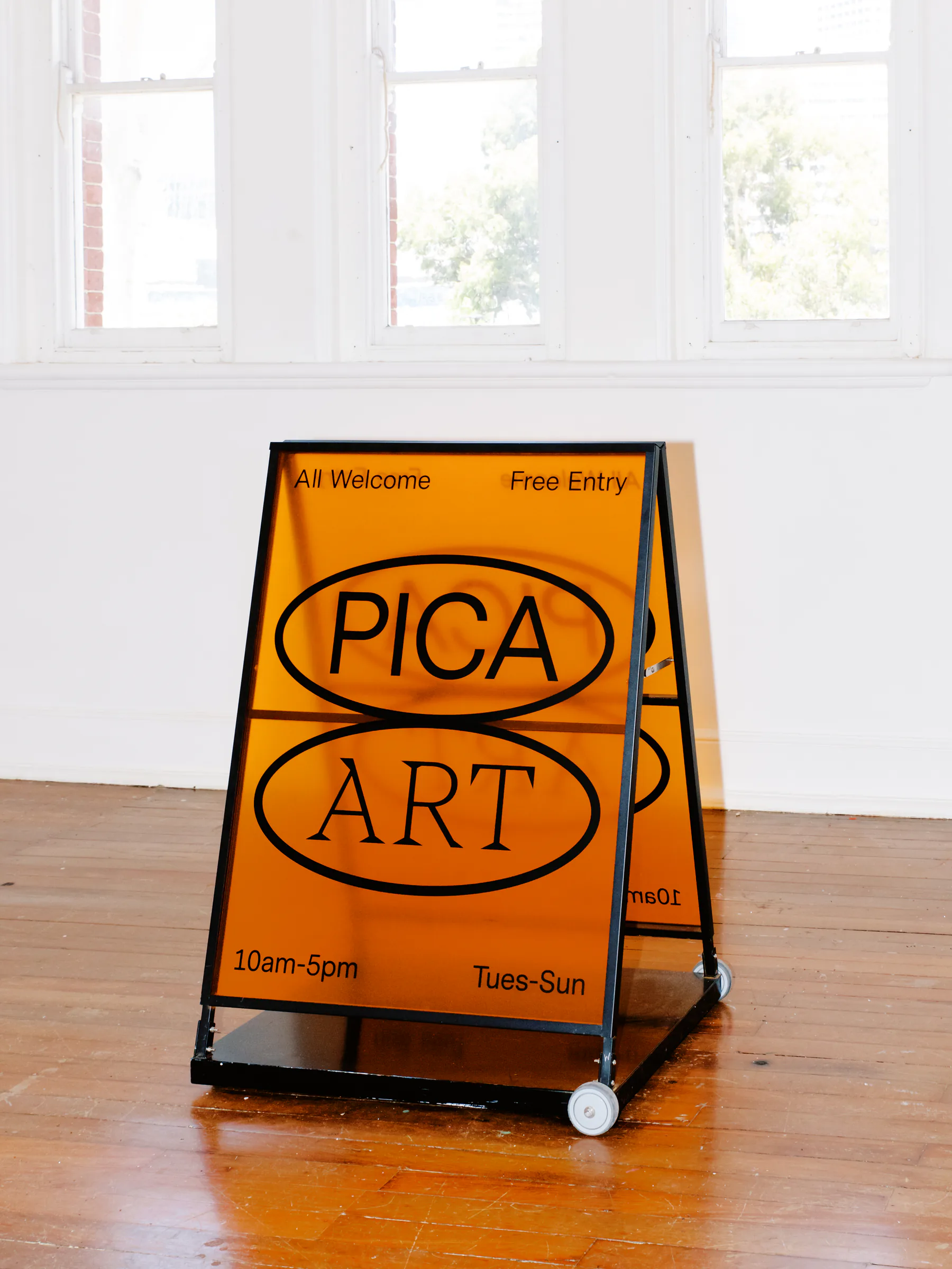 Orange PICA Art A-frame sign in the gallery