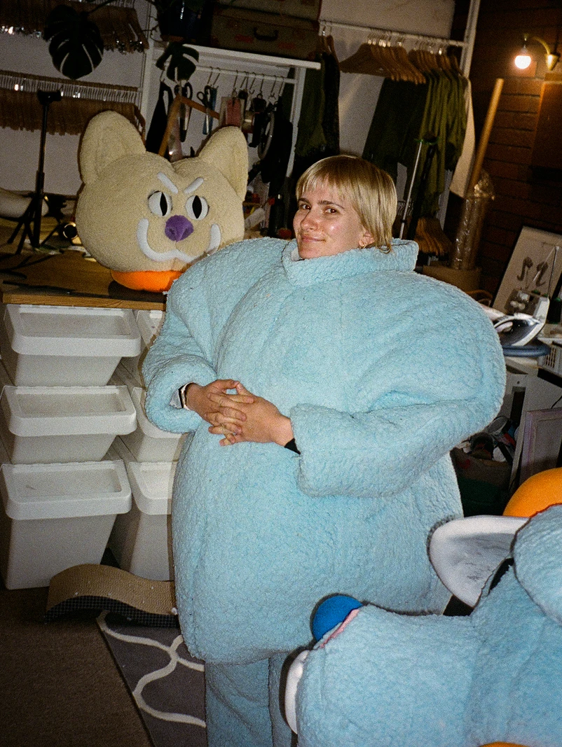 Working with the oversized blue mascot costume body during a studio fitting