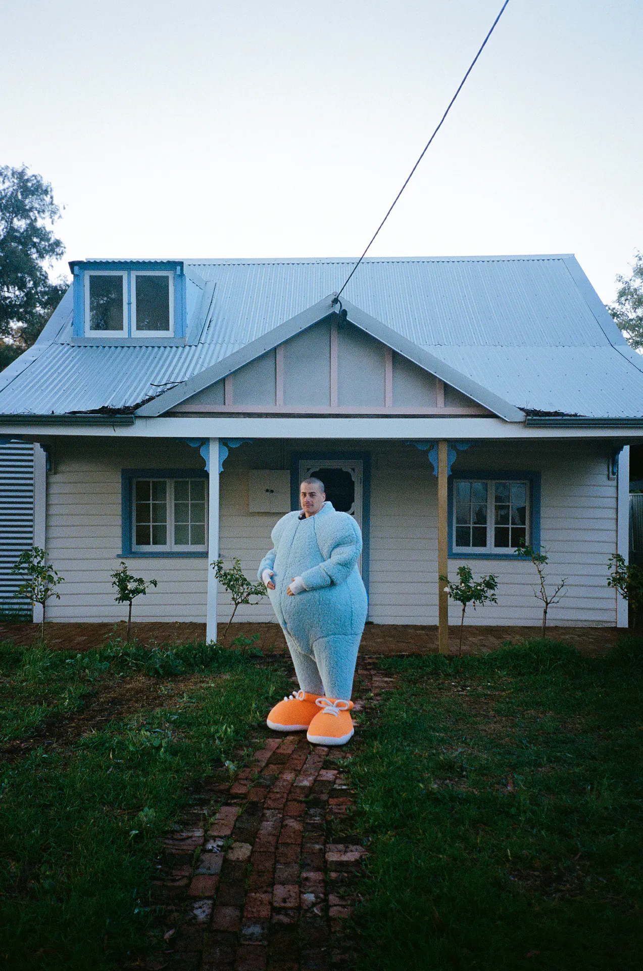 The full-size blue Sports Dreams mascot standing outside a house