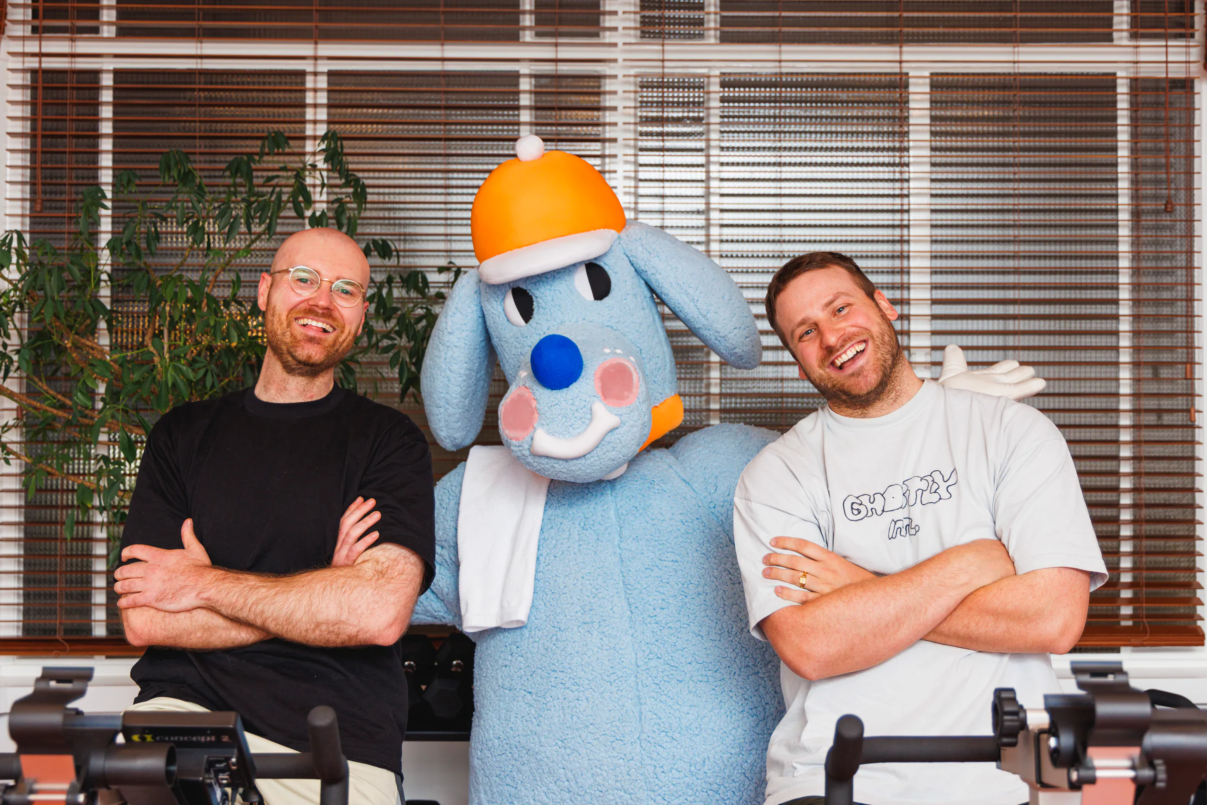 Two Sports Dreams collaborators posing with the blue mascot outside a house